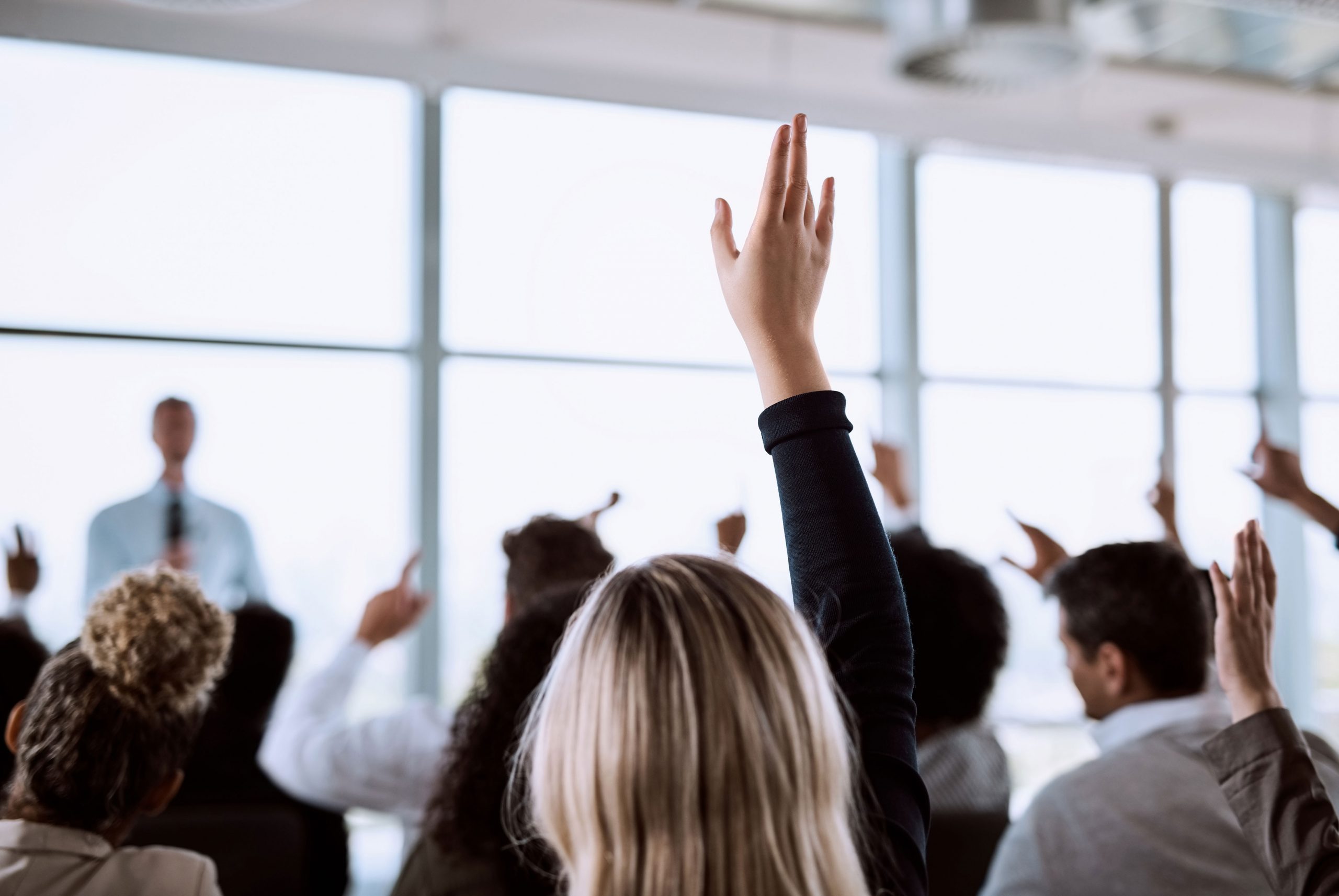 Investors raising their hands to ask questions during a conference
